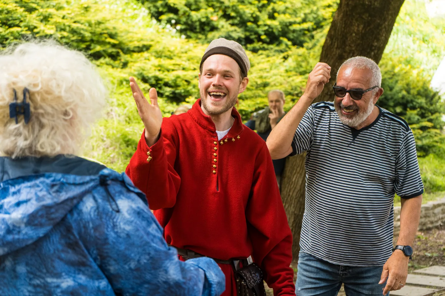 Smiling host in medieval-inspired costumes during an outdoor event