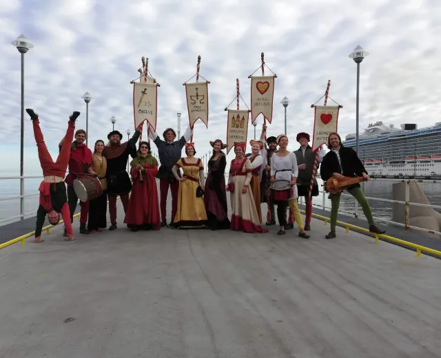 Medieval performers and hosts holding banners on the Tallinn waterfront